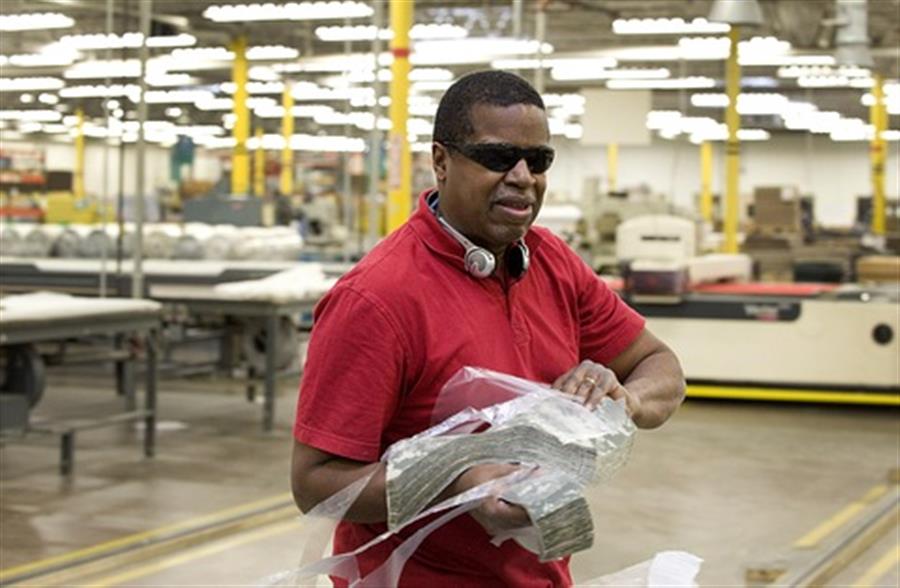 A man transporting fabric in a manufacturing plant. 